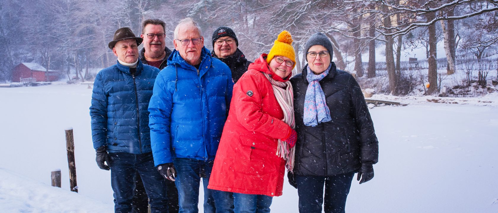 Lämpimästi pukeutuneet ja hymyilevät Kemiönsaaren omakotiyhdistyksen aktiivit seisovat laiturilla lumisella rannalla.