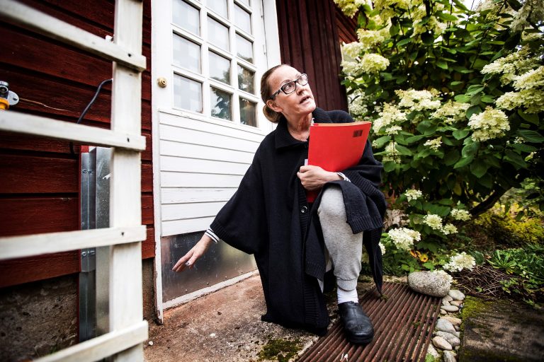 Asumisliiton Hannele Rämö on tarkastukäynnillä. Hän tarkastelee punaisen talon kuistilla kosteudesta kärsineitä puisia oven karmeja.