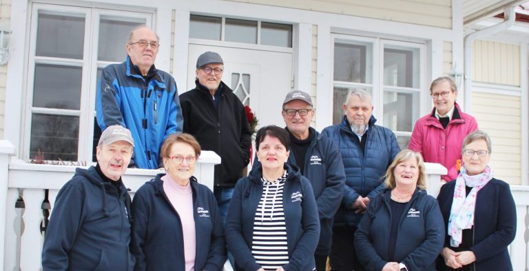 Kuvassa kymmenen henkilöä seisoo talon edustalla. He ovat Pertti Kiuru, Matti Lindfors, Seija Salo, Jarmo Käkelä, Kirsi Siljamäki, Antti Siljamäki, Jorma Salo, Päivi Siljamäki, Eeva Lindfors ja Leila Kiuru.