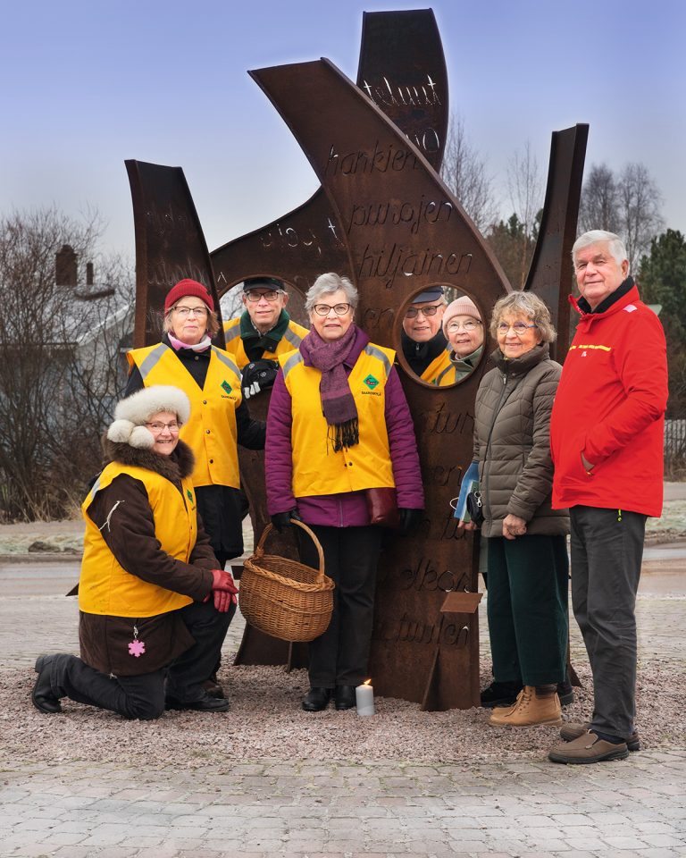 Kuvassa kahdeksan omakotiaktiivia taideteoksen vieressä.